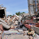 A boy sits on the rubble of a building that collapsed after an earthquake as he takes shelter from the sun in Pidie Jaya. (Image: AP/Heri Juanda)